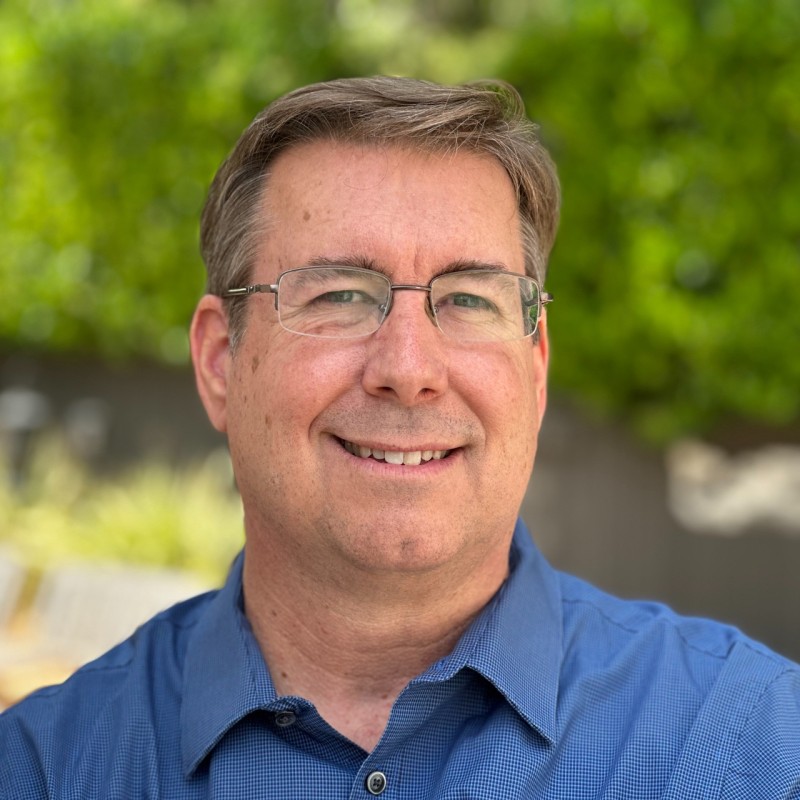 Craig Chrisney in a blue shirt outdoors, greenery blurred behind him