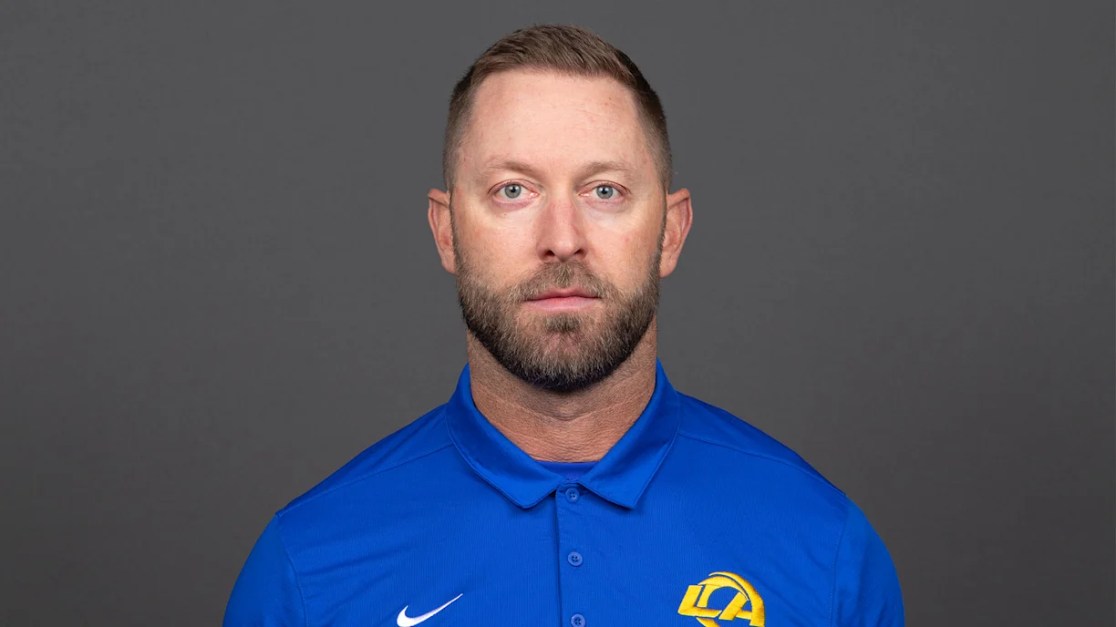 Kliff Kingsbury in a blue Los Angeles Rams polo against a grey backdrop