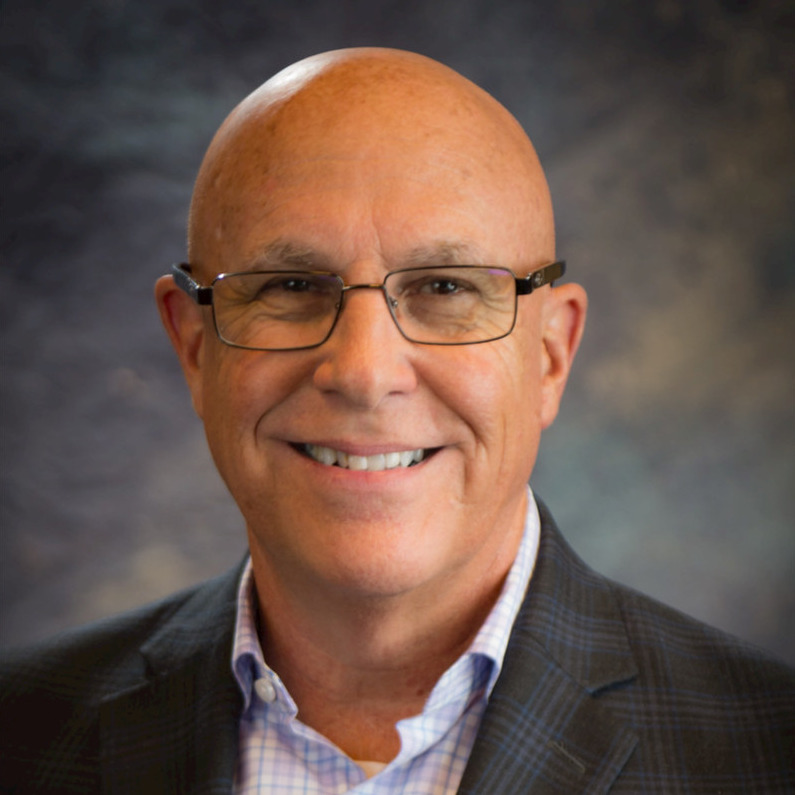 Larry Lynch in a checked shirt and dark blazer, smiling