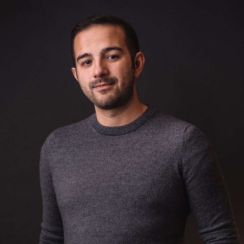 William Kasel in a grey crewneck sweater against a dark backdrop